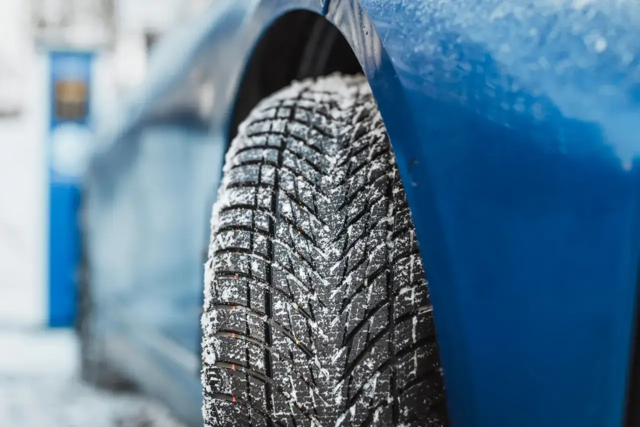 Nahaufnahme eines blauen Autos mit Schnee auf dem Reifen. Der Reifen ist ein Goodyear UltraGrip Performance 3, bereit für den Test.