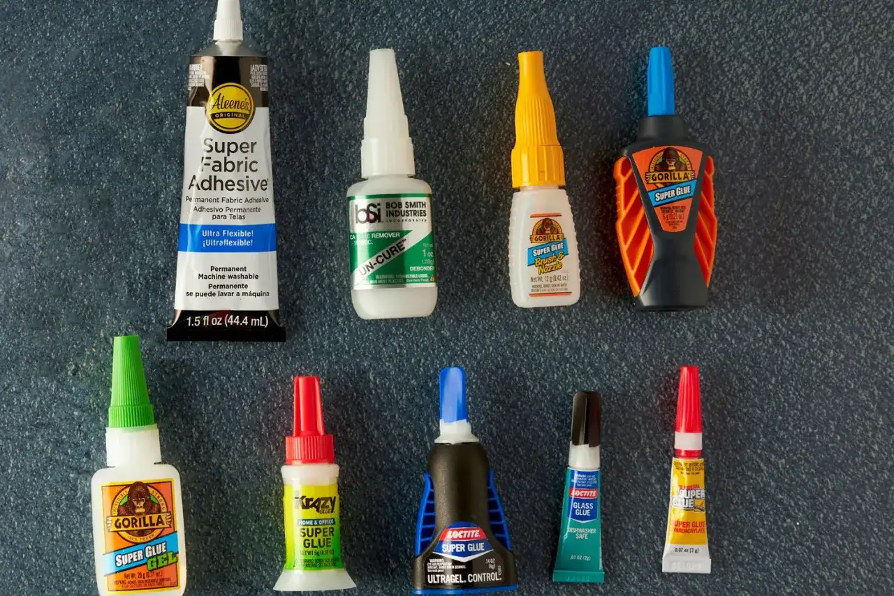 A collection of super glues and adhesives, including Gorilla Glue and Loctite, are laid out, hinting at what is the strongest adhesive glue for various needs.
