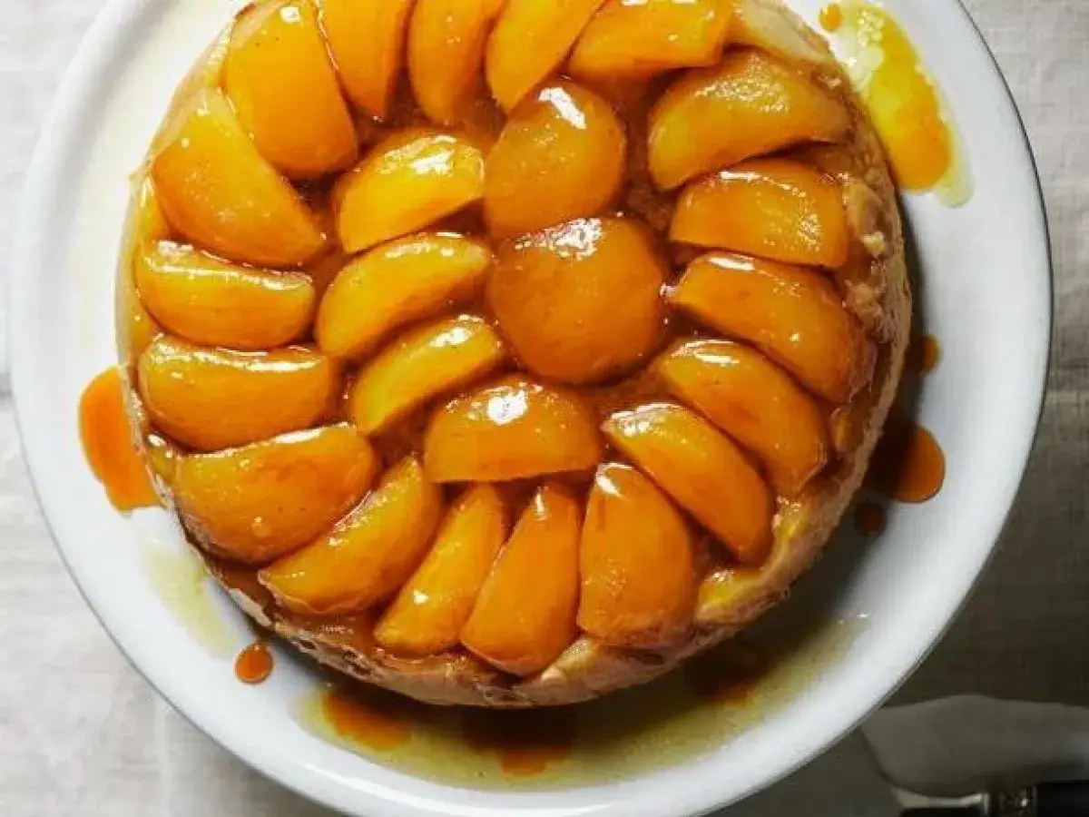 Tarte Tatin dorata e lucida, con spicchi di frutta caramellata disposti a raggiera su una base croccante.