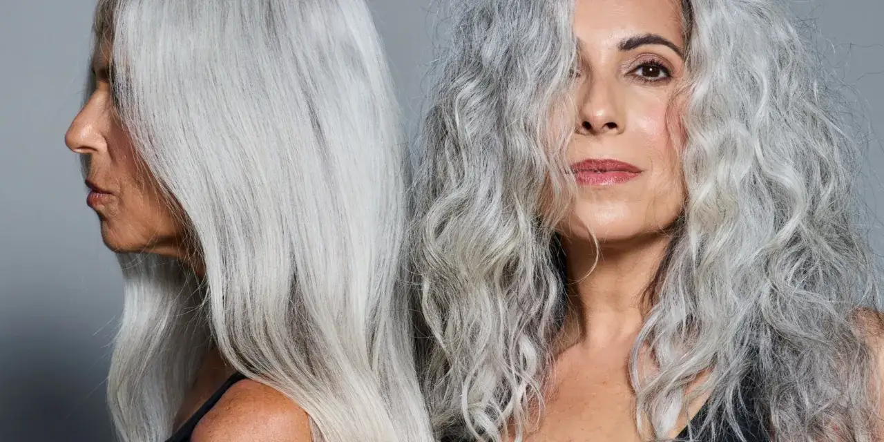 Dos mujeres con cabello plateado, unas canas que lucen con orgullo. Una de perfil, la otra mirando a cámara.