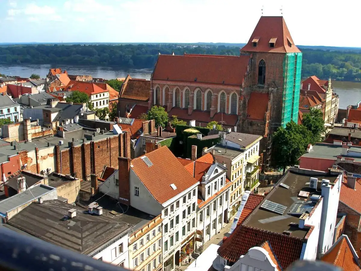 Widok na średniowieczny zesp&oacute;ł miejski Torunia z dominującą ceglaną katedrą i rzeką w tle.