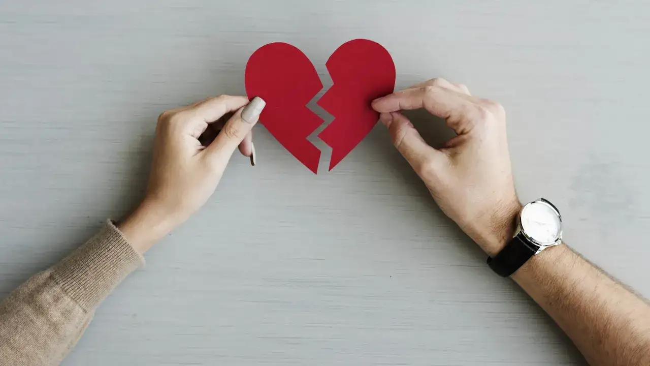 Mani che tengono un cuore rosso spezzato, simbolo di un profondo bisogno di amore e di un legame da ricomporre.