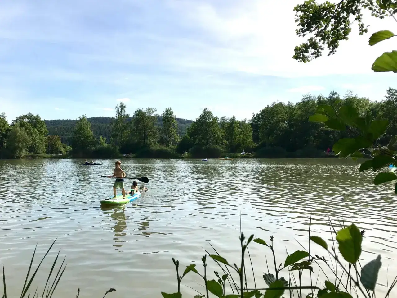 Kinder genie&szlig;en das Stand-Up-Paddling auf dem Badesee Ludwigsburg.