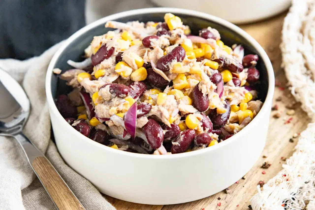 Herzhafter kidneybohnen salat mit Thunfisch, Mais und roten Zwiebeln, serviert in einer wei&szlig;en Sch&uuml;ssel.