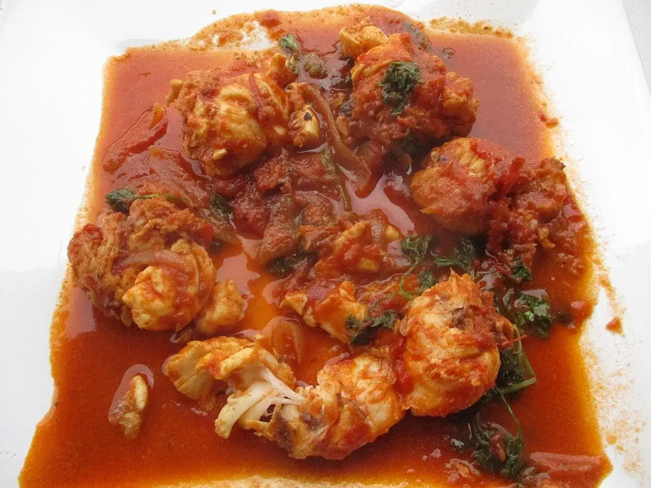 Morceaux de poisson enrob&eacute;s d'une sauce armoricaine savoureuse, avec des herbes vertes parsem&eacute;es.