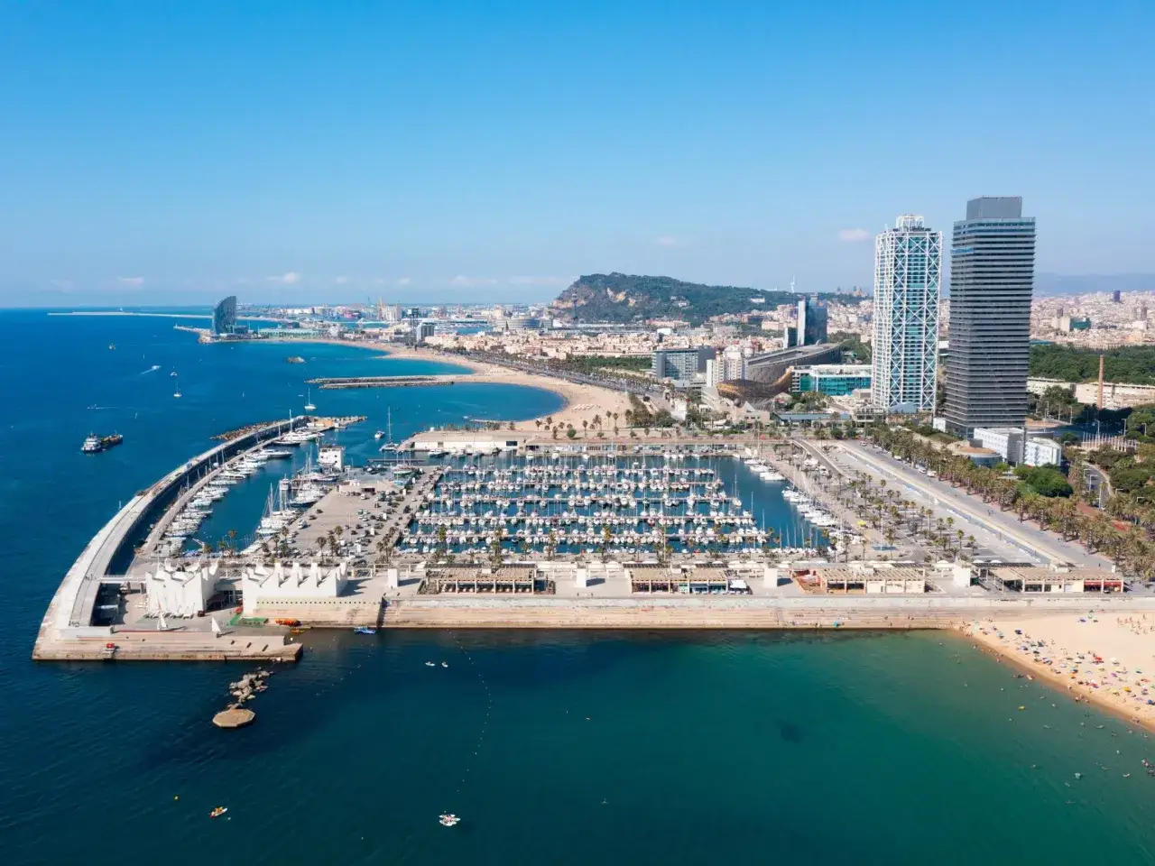 Widok na Barcelonę z portem pełnym jachtów i plażą. Czy w Hiszpanii jest bezpiecznie? Tak, to popularny i bezpieczny kierunek turystyczny.