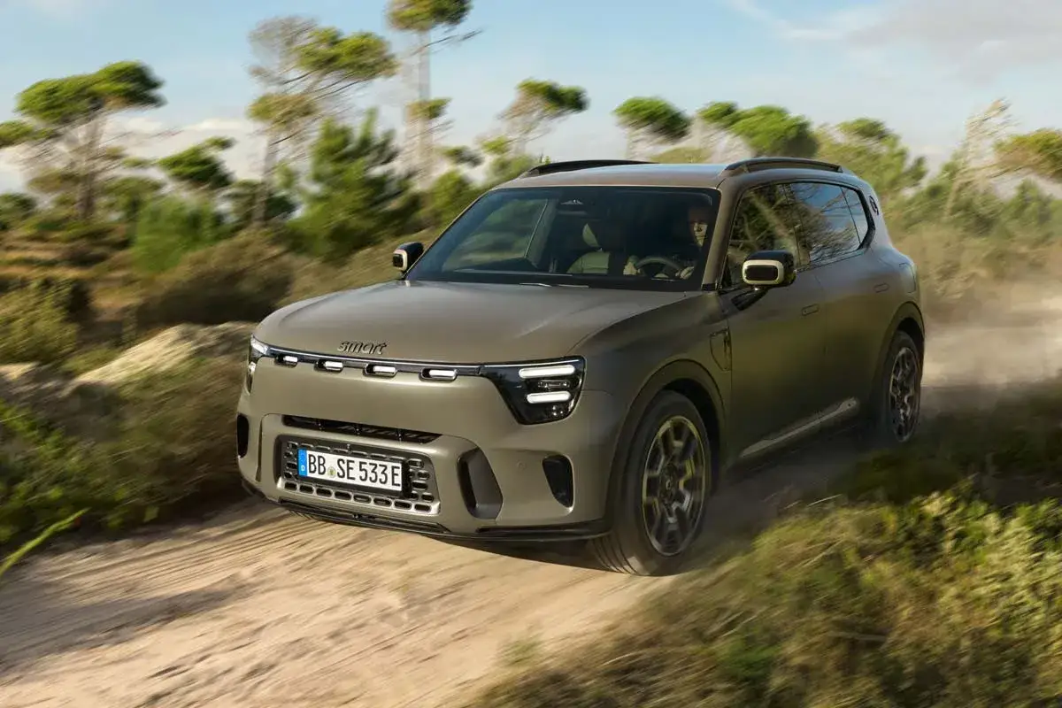 En smart 5-d&ouml;rrars SUV k&ouml;r p&aring; en grusv&auml;g genom ett torrt landskap med tr&auml;d.