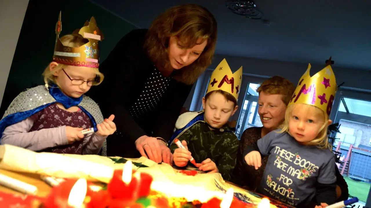 Evangelische Sternsinger basteln. Kinder mit Kronen und Umhängen malen, eine Frau hilft.
