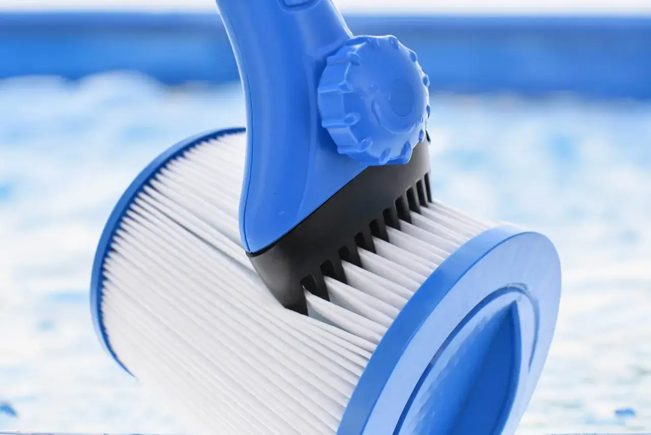 Un outil bleu nettoie un filtre de jacuzzi. L'entretien régulier assure une eau pure pour votre détente.