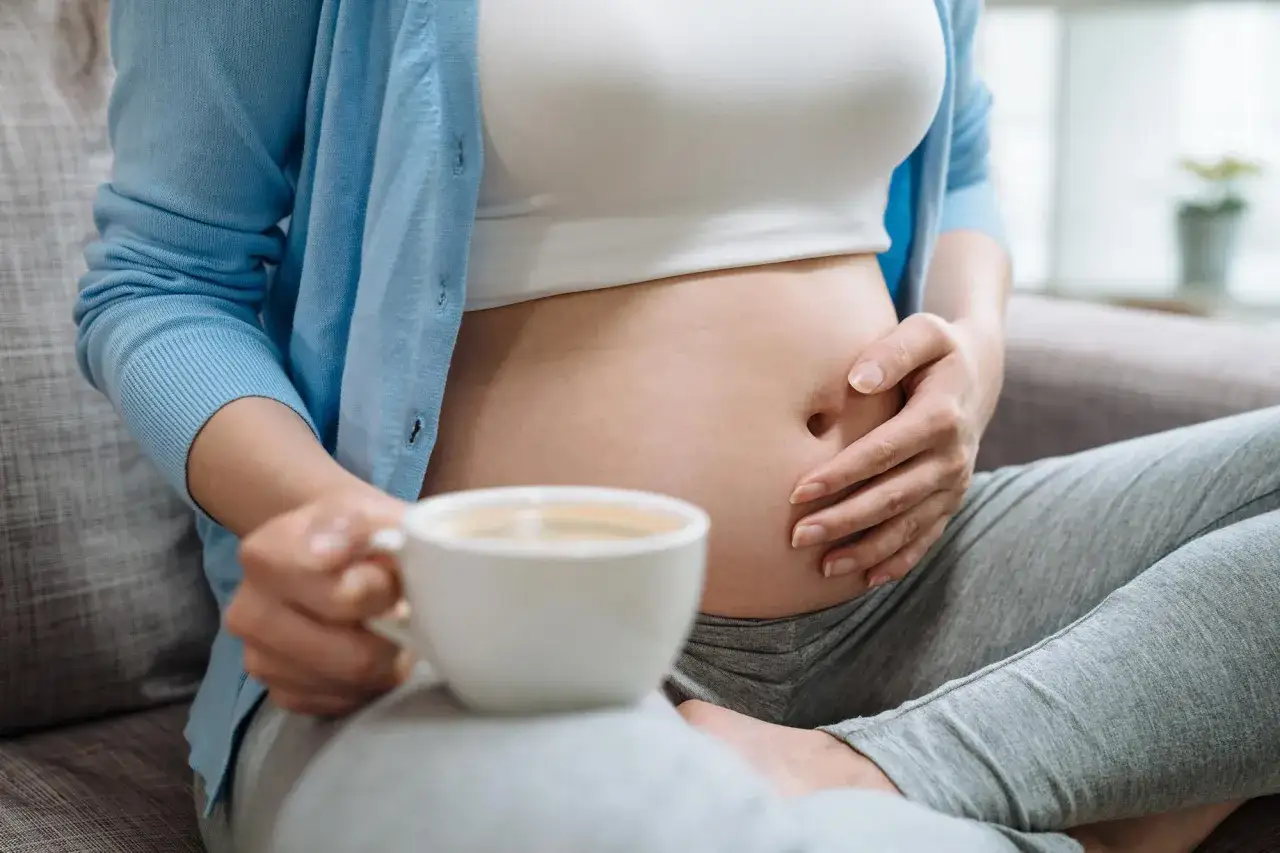 Donna incinta tiene una tazza di caffè, godendosi un momento di relax.