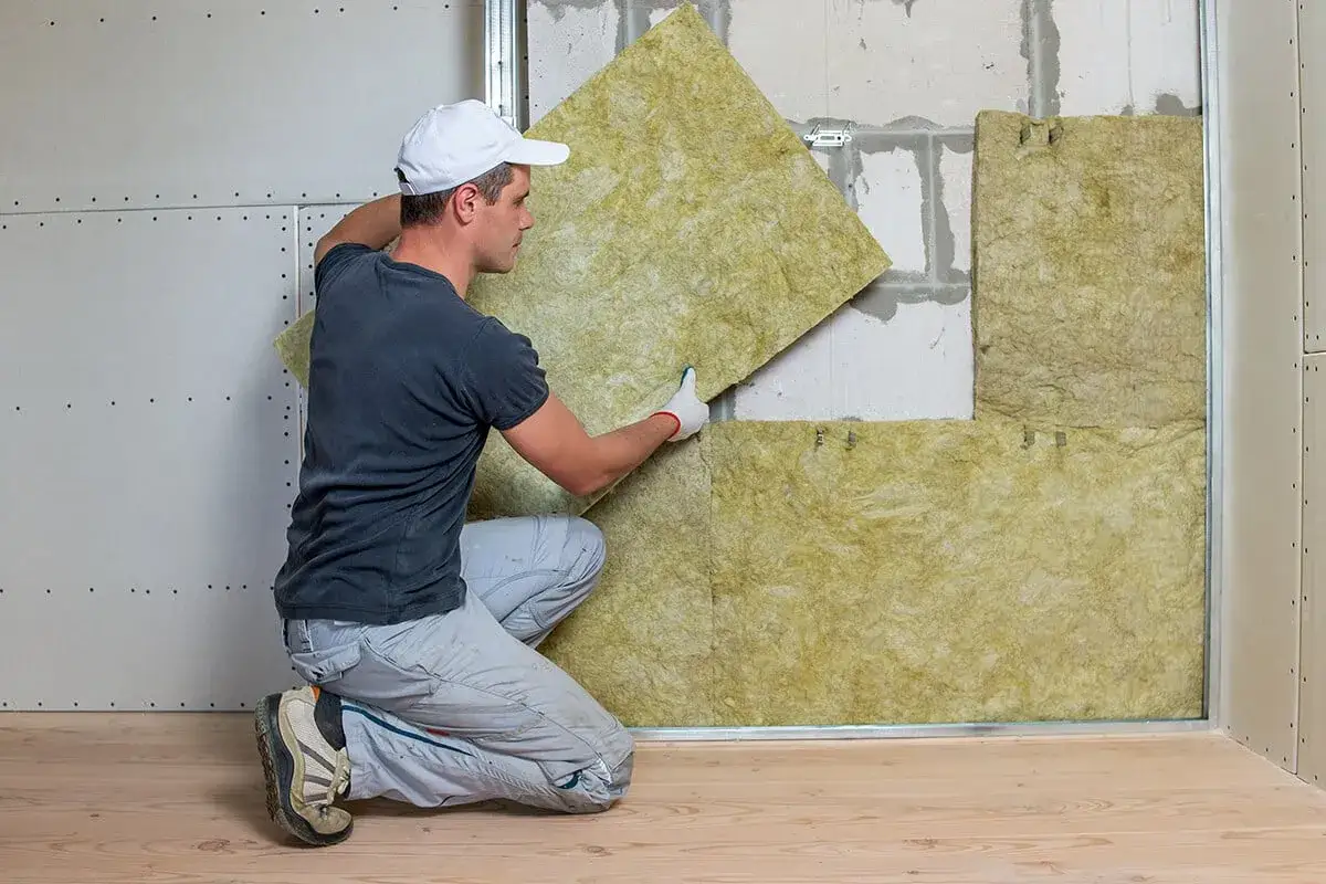 Un ouvrier installe un isolant pour am&eacute;liorer l'isolation phonique ou acoustique d'un mur.