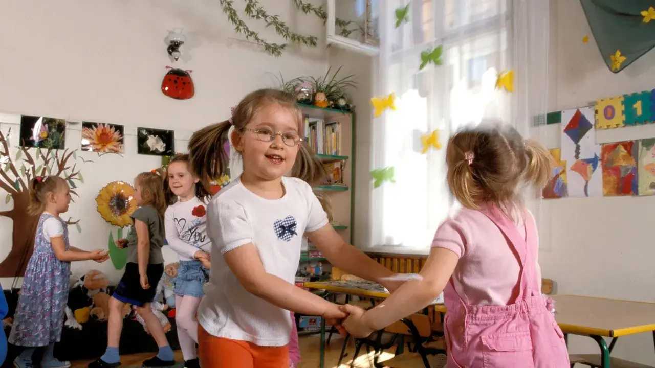 Ni&ntilde;os jugando y bailando en un aula decorada, como en un peque&ntilde;o teatro.