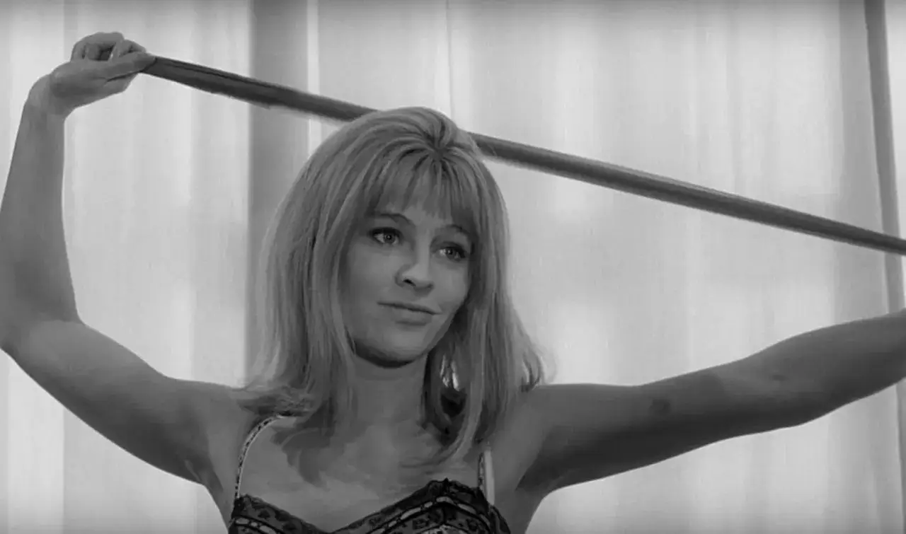 Una donna bionda con un sorriso malizioso tiene un filo di nylon, un'immagine che evoca il fascino del cinema d'autore, un vero cinema libero.