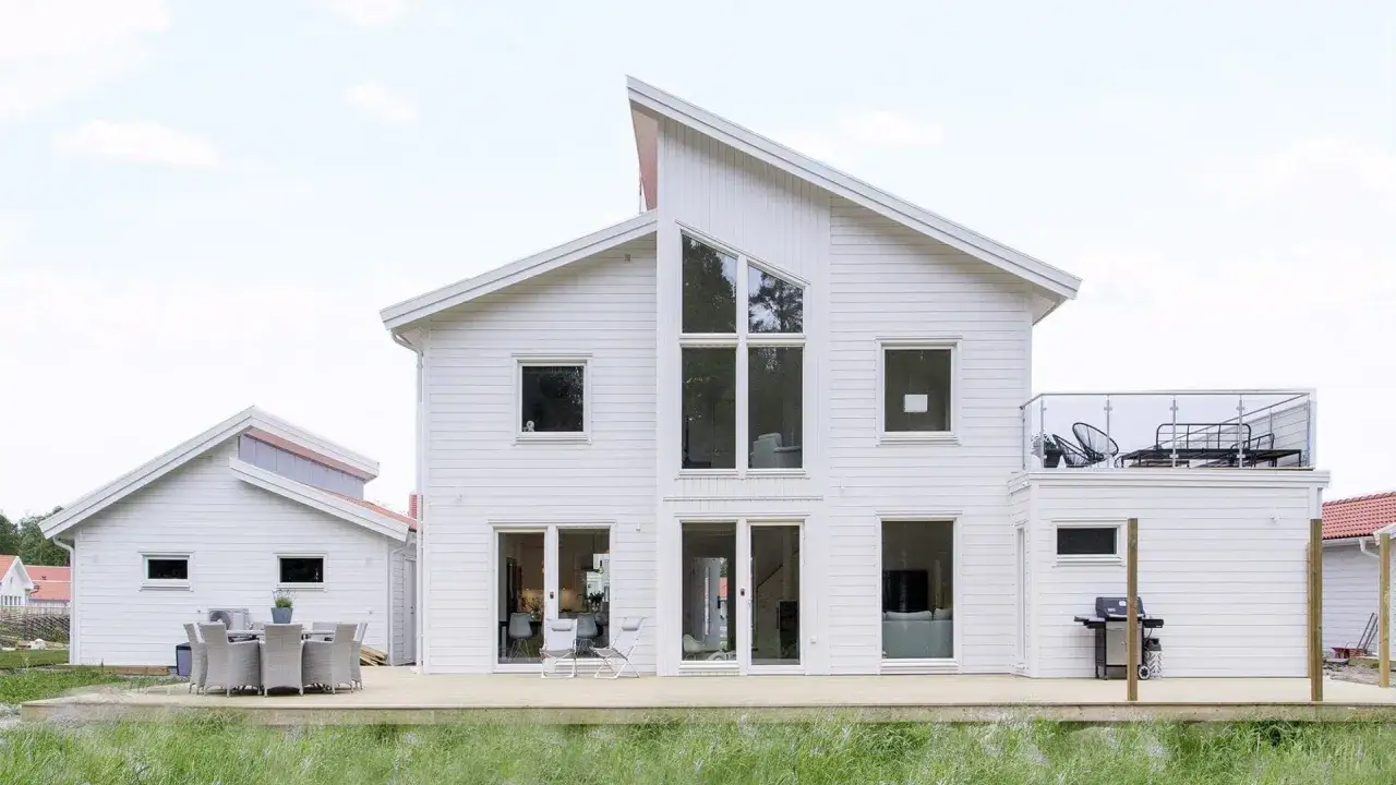 Vitt modernt hus med stora fönster och altan. En bra byggare har skapat detta drömhem.