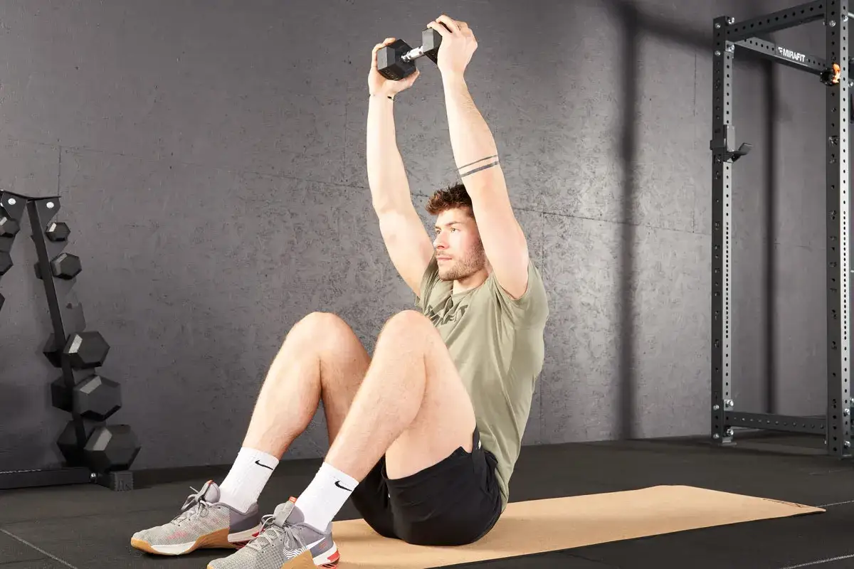 Homme faisant un crunch abdo avec haltère, assis sur un tapis de gym.