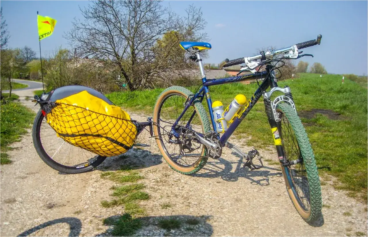 Gotowy na wyprawę rower z sakwami, ż&oacute;łty bagaż zabezpieczony siatką, flaga 