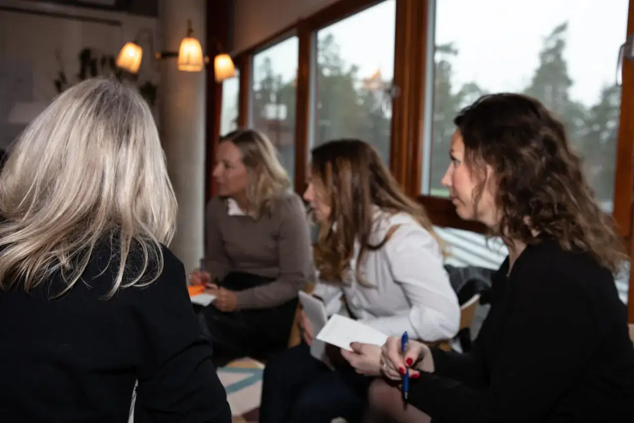 Kvinnor diskuterar idéer vid ett bord, vilket visar vikten av kommunikation på arbetsplatsen.