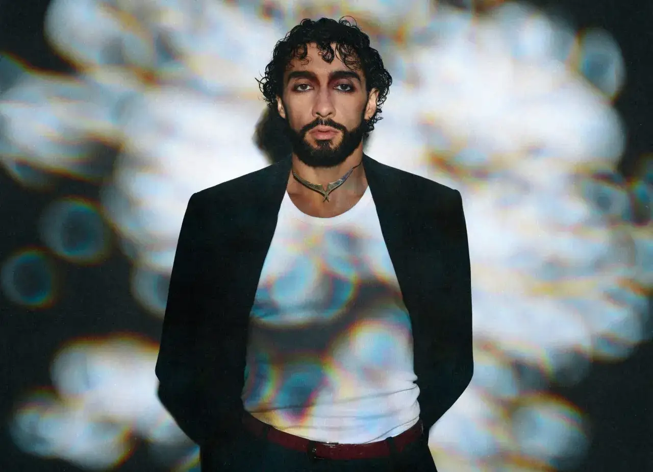 Sofiane Pamart in Berlin, mit dunklem Haar und Bart, tr&auml;gt einen schwarzen Blazer &uuml;ber einem wei&szlig;en Shirt mit einem auff&auml;lligen Muster.