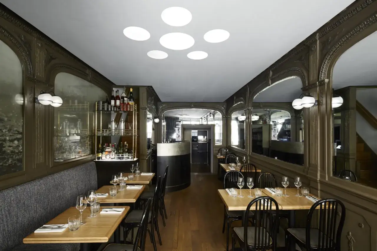 Eleganckie wnętrze, co to jest bistro? Stoliki, krzesła, bar z butelkami alkoholu i lustra tworzą przytulną atmosferę.