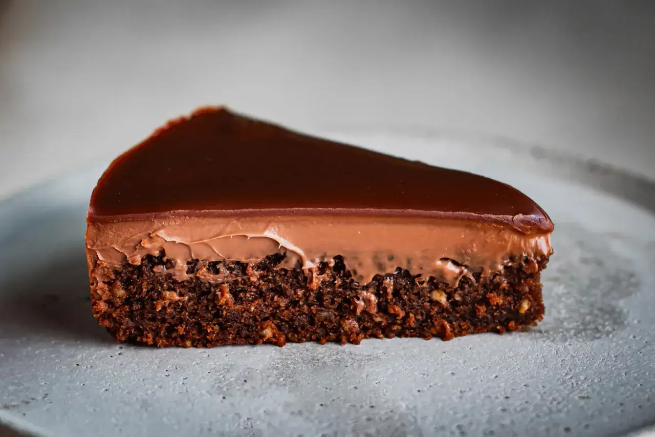 Une part de gâteau fourré chocolat, avec une base dense, une mousse onctueuse et un glaçage brillant. Un délice gourmand.