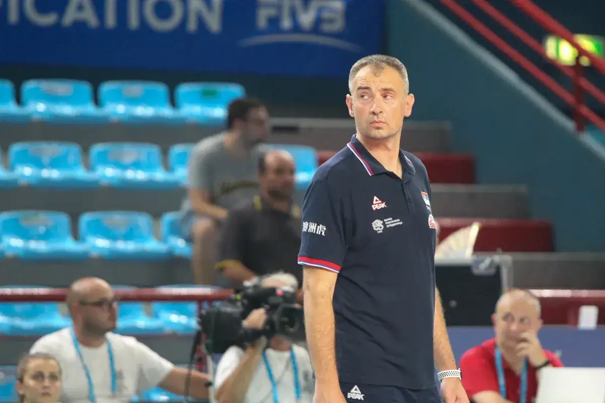 Trener siatk&oacute;wki Nikola Grbić w koszulce z logo Peak, obserwuje mecz z ławki.