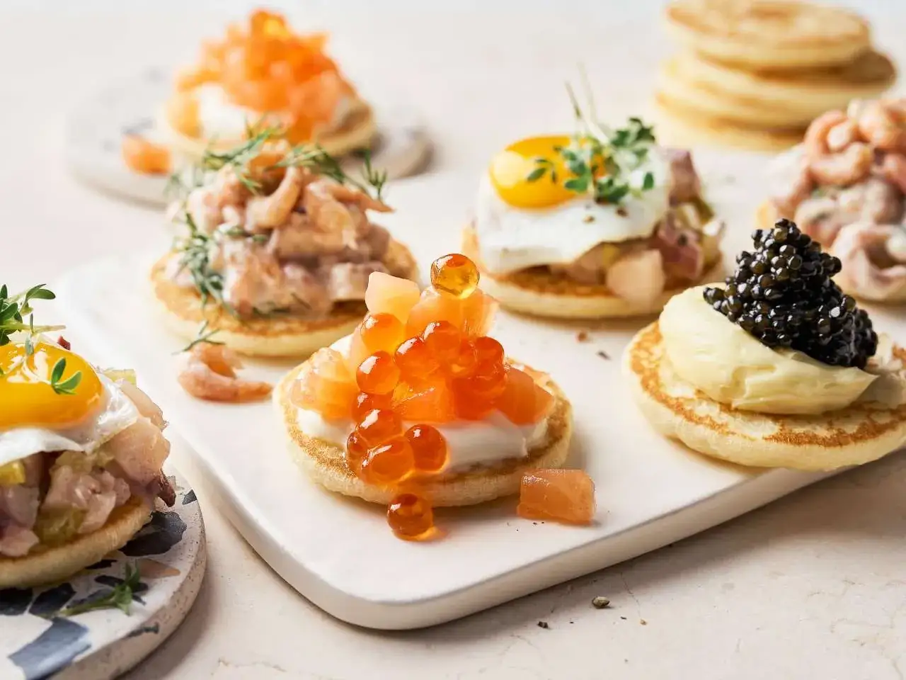 Kleine Pfannkuchen mit Kaviar, Lachsrogen, Garnelen und Spiegelei &ndash; k&ouml;stliche Kaviar Rezepte Vorspeise.