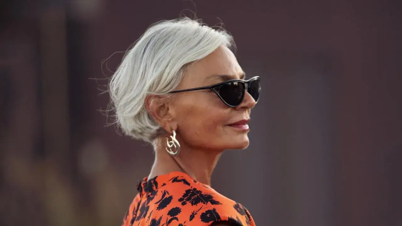 Elegante Frau mit grauem Kurzhaarschnitt, Sonnenbrille und auffälligem Ohrring. Ein Beispiel für stilvolle kurzhaarfrisuren frauen ab 60.