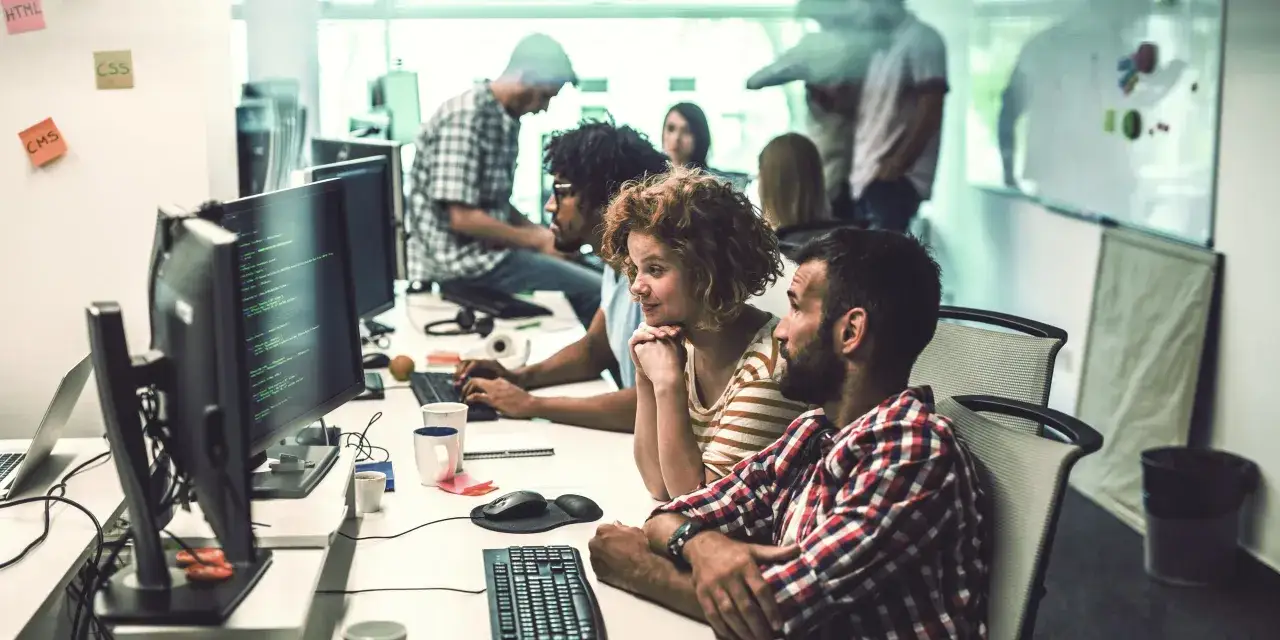 Teamwork im B&uuml;ro: Studierende des IU Master Wirtschaftsinformatik arbeiten konzentriert an ihren Computern.