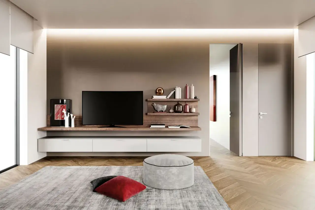 Soggiorno moderno con mobile TV sospeso, mensole con decorazioni e un pouf tortora rgb.