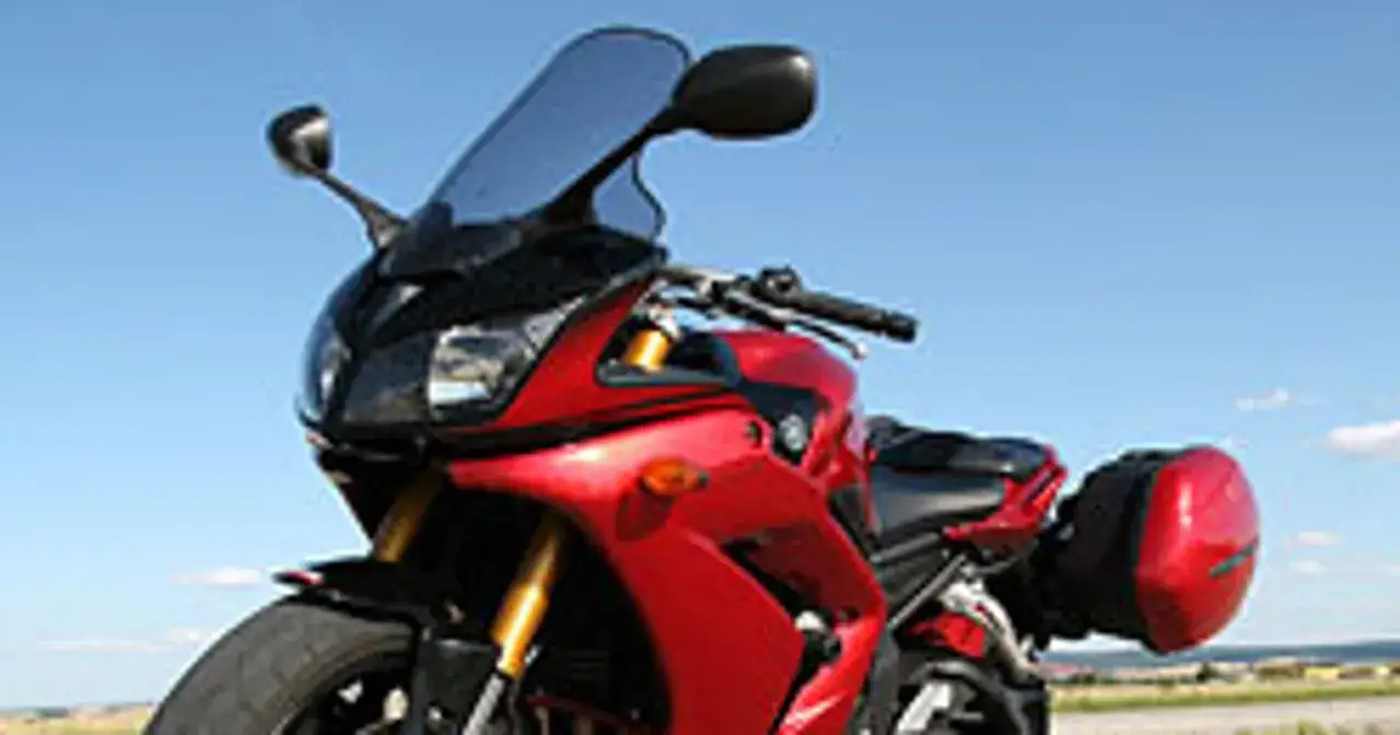 Czerwony motocykl Yamaha FZ1 z kuframi, gotowy na podróż pod błękitnym niebem.