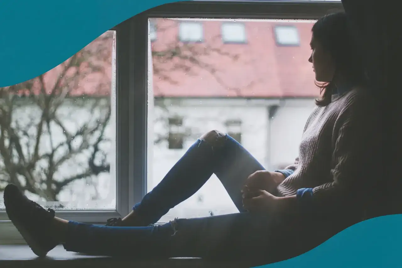 En person sitter vid ett regnigt fönster, funderar på hur kommer man ur en depression.