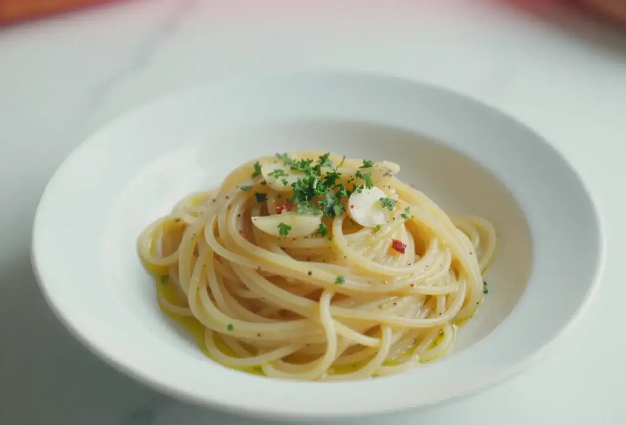 Pyszne spaghetti aglio e olio, z czosnkiem, natką pietruszki i płatkami chili, polane oliwą.