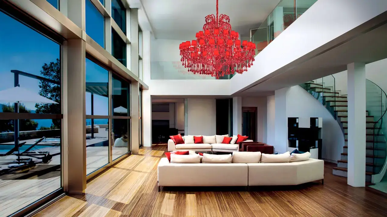Lussuoso soggiorno moderno con divani bianchi, scala a chiocciola e un'imponente lampadario rosso. Ottime idee illuminazione soggiorno moderno.