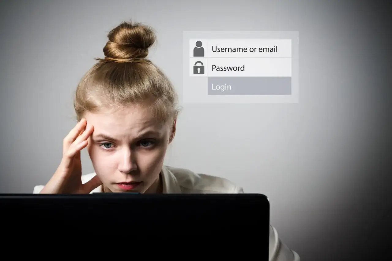Zestresowana kobieta przed ekranem laptopa, próbująca złamać hasło metodą brute force.