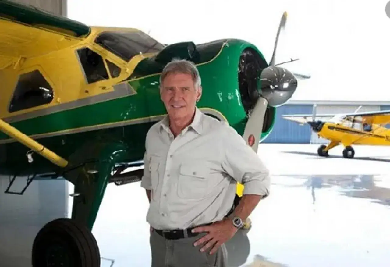 Harrison Ford, w wieku, który wciąż pozwala mu na loty, pozuje przy swoim samolocie.
