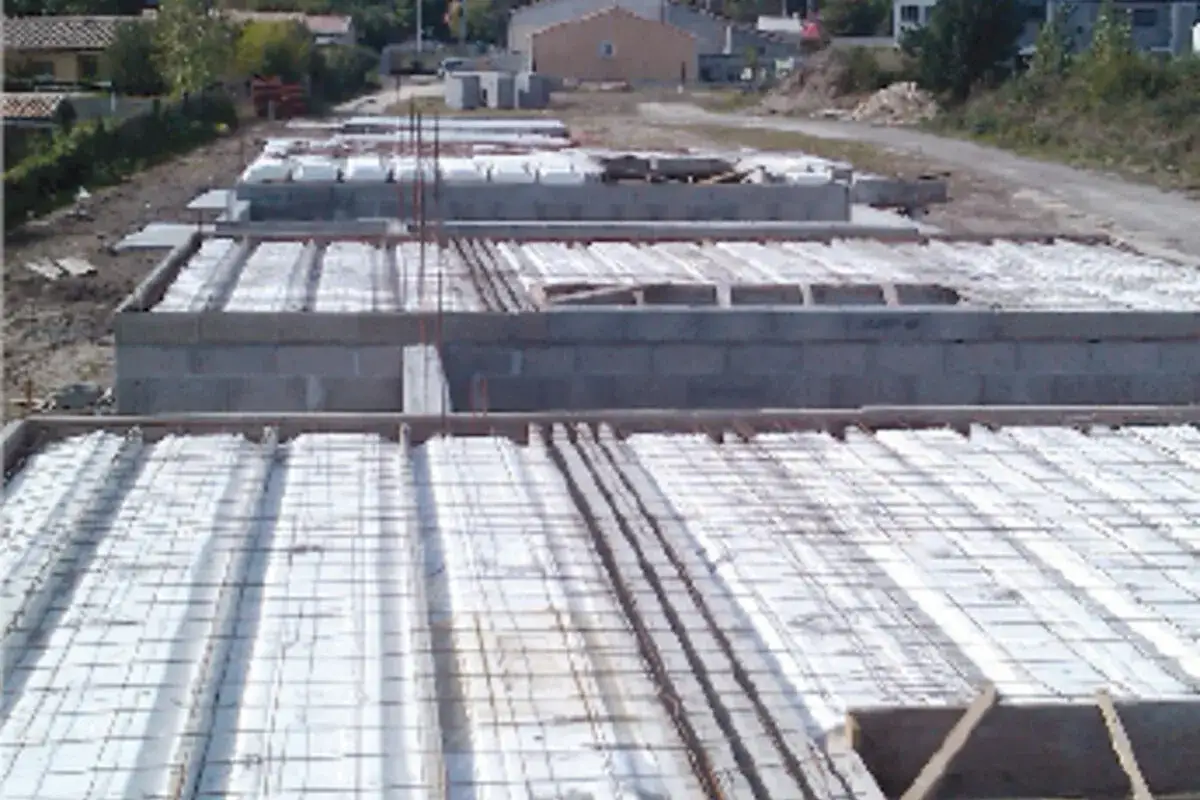 Chantiers de construction avec des fondations en blocs de b&eacute;ton et des &eacute;l&eacute;ments de dalle de compression pr&ecirc;ts &agrave; &ecirc;tre coul&eacute;s.