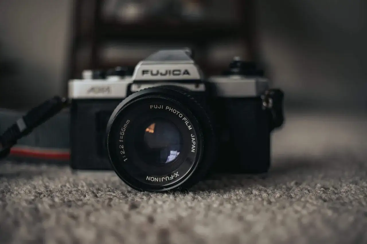 Aparat Fujica z obiektywem X-FUJINON 55mm. Zastanawiasz się, w kt&oacute;rym roku wynaleziono aparat fotograficzny?