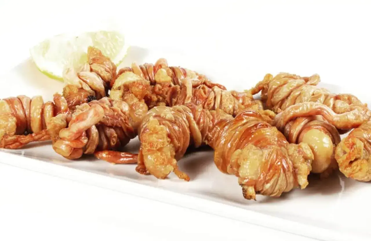 Gallinejas y entresijos fritos, crujientes y dorados, servidos con una rodaja de lim&oacute;n.