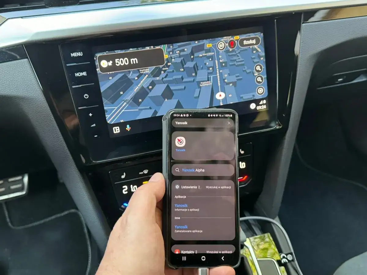 Instalacja Yanosika na Honda Connect. Telefon z aplikacją Yanosik w dłoni, nawigacja w tle.