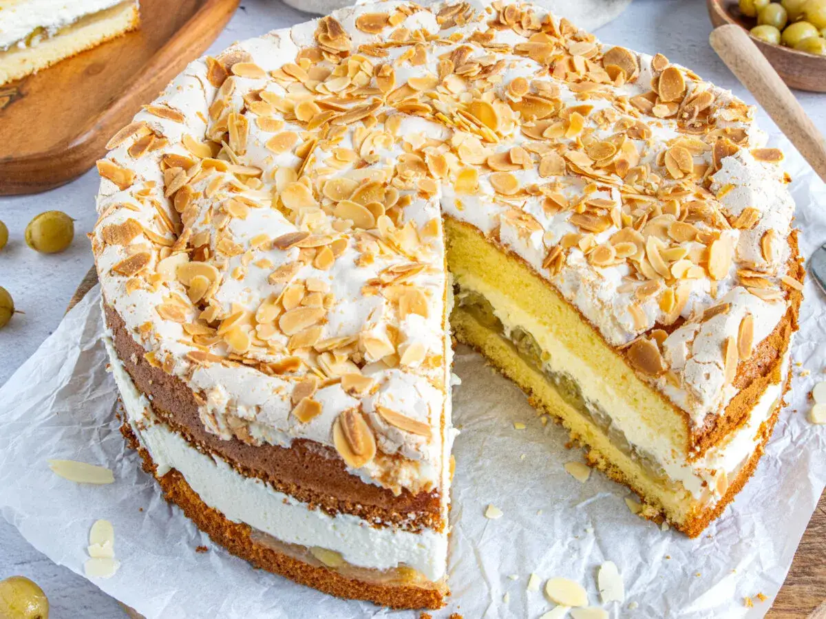 Ein k&ouml;stlicher Stachelbeer Baiser Kuchen mit Biskuitb&ouml;den, Sahne und Mandelsplittern.