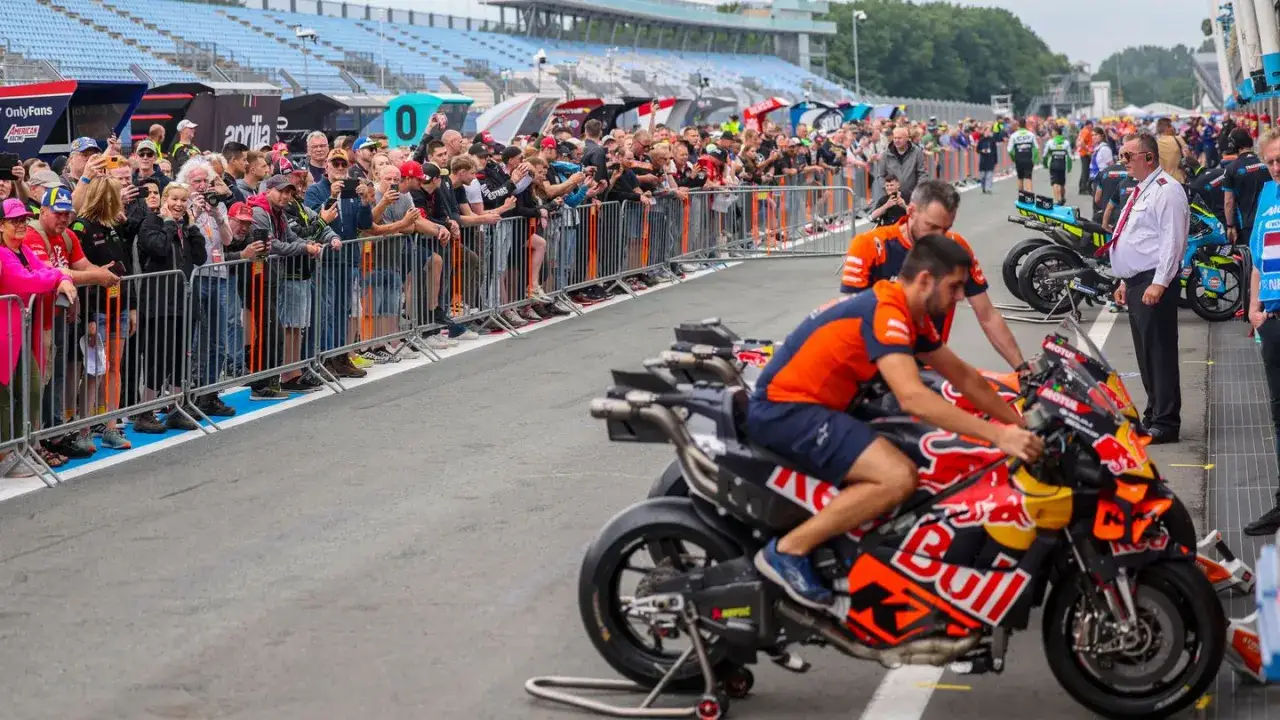 Aficionados observan un motogp test en la pista. Pilotos preparan sus motos de carreras.