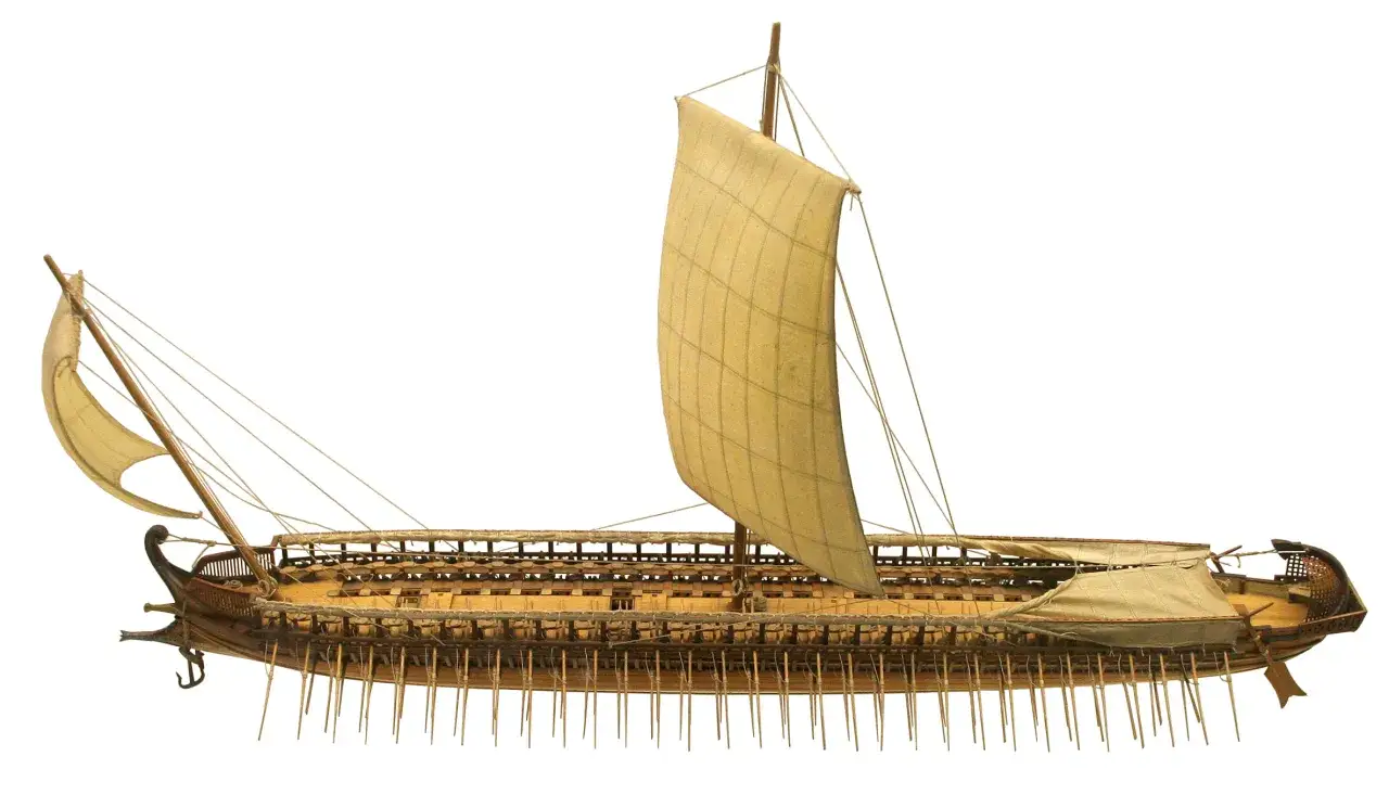 Ein detailgetreues Modell eines antiken Dreiruderers mit Segeln und Rudern, bereit zur Seeschlacht.