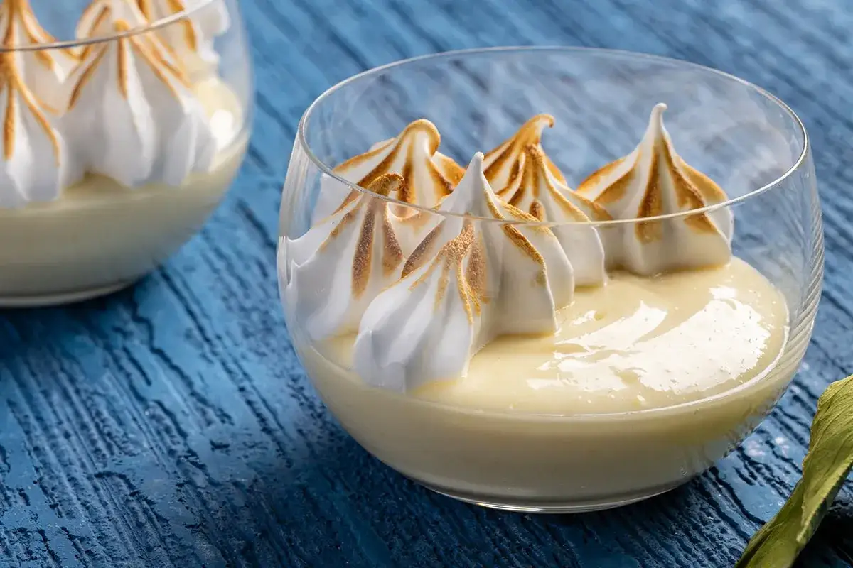 Delizioso dessert in coppa: una soffice mousse al limone coronata da meringa dorata e caramellata.