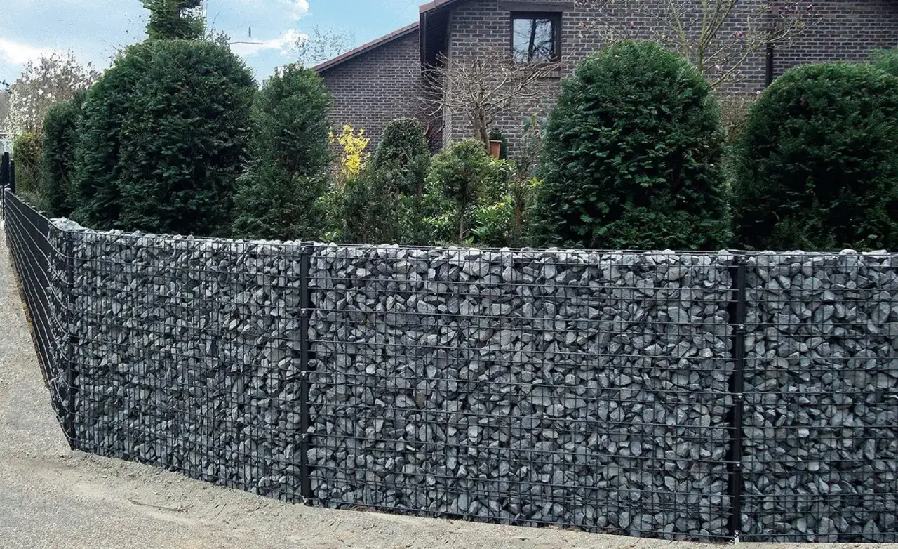 Nowoczesny mur oporowy z kamienia w gabionach, idealny jako fundament pod ogrodzenie.