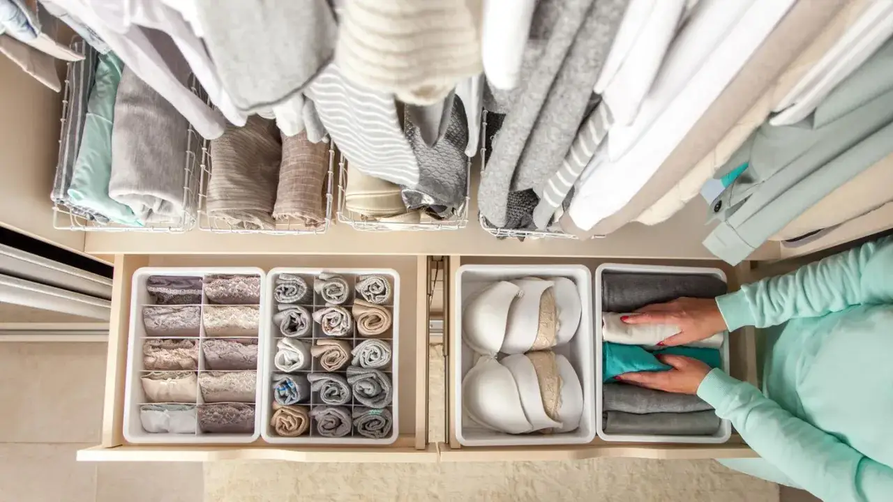 Kleiderschrank ausmisten: Wo anfangen? Ordentliche Schubladen mit Unterwäsche, Socken und BHs. Oben hängen Pullover und Kleider.