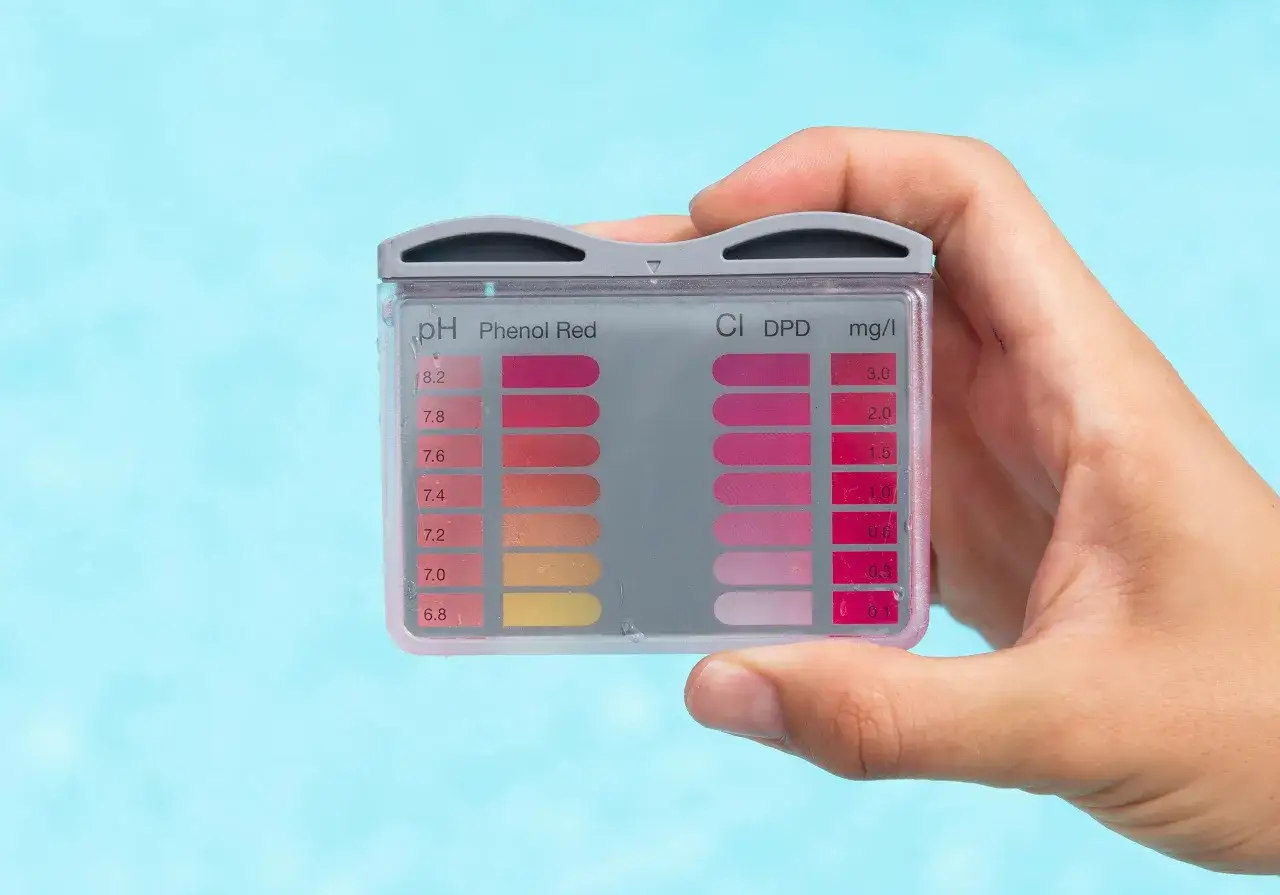 Hand hält Teststreifen zur Messung des ph-wert pool. Farben zeigen den Säuregehalt an.