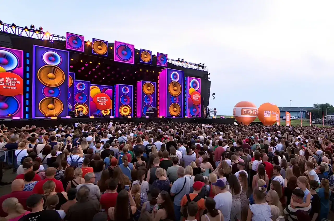 Tłumy ludzi na **radom koncert dzisiaj**! Wielka scena z podświetlanymi głośnikami i pomarańczowe balony w tle.
