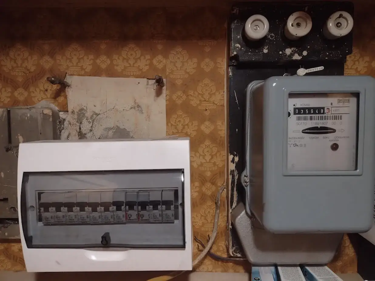 Obok licznika energii elektrycznej znajduje się rozdzielnica z bezpiecznikami, a nad nimi stary bezpiecznik przedlicznikowy.