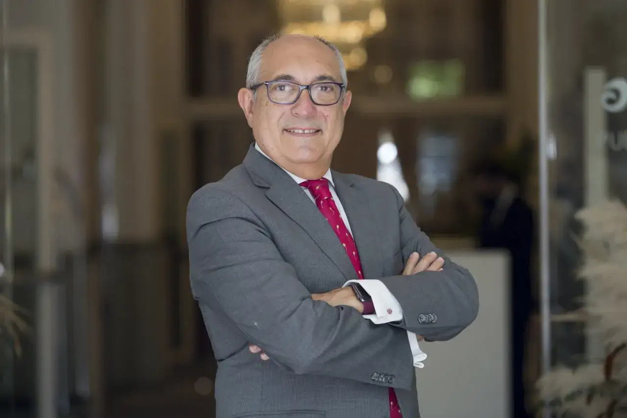 Hombre con traje gris y corbata roja, con los brazos cruzados. Posiblemente un participante en un **advanced management program**.