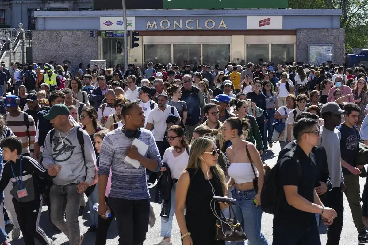 Una multitud de **personas** camina frente a la estación de metro Moncloa.